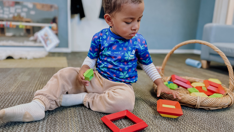 Child playing with pyramid stacker in the nursery at Little Wonders Timaru